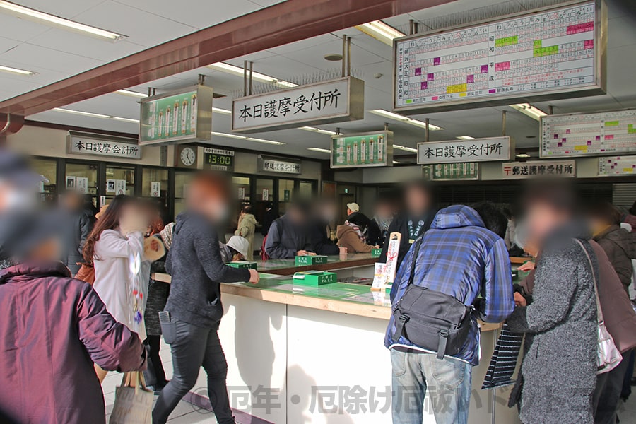 お護摩受付所内での申込記入所と申込用紙に記入を進める多くの参拝者の様子