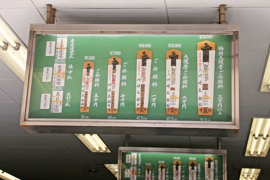 川崎大師 同お護摩受付所内に掲げられているお護摩祈祷の御札（護摩札）と祈祷料金額案内掲示の様子